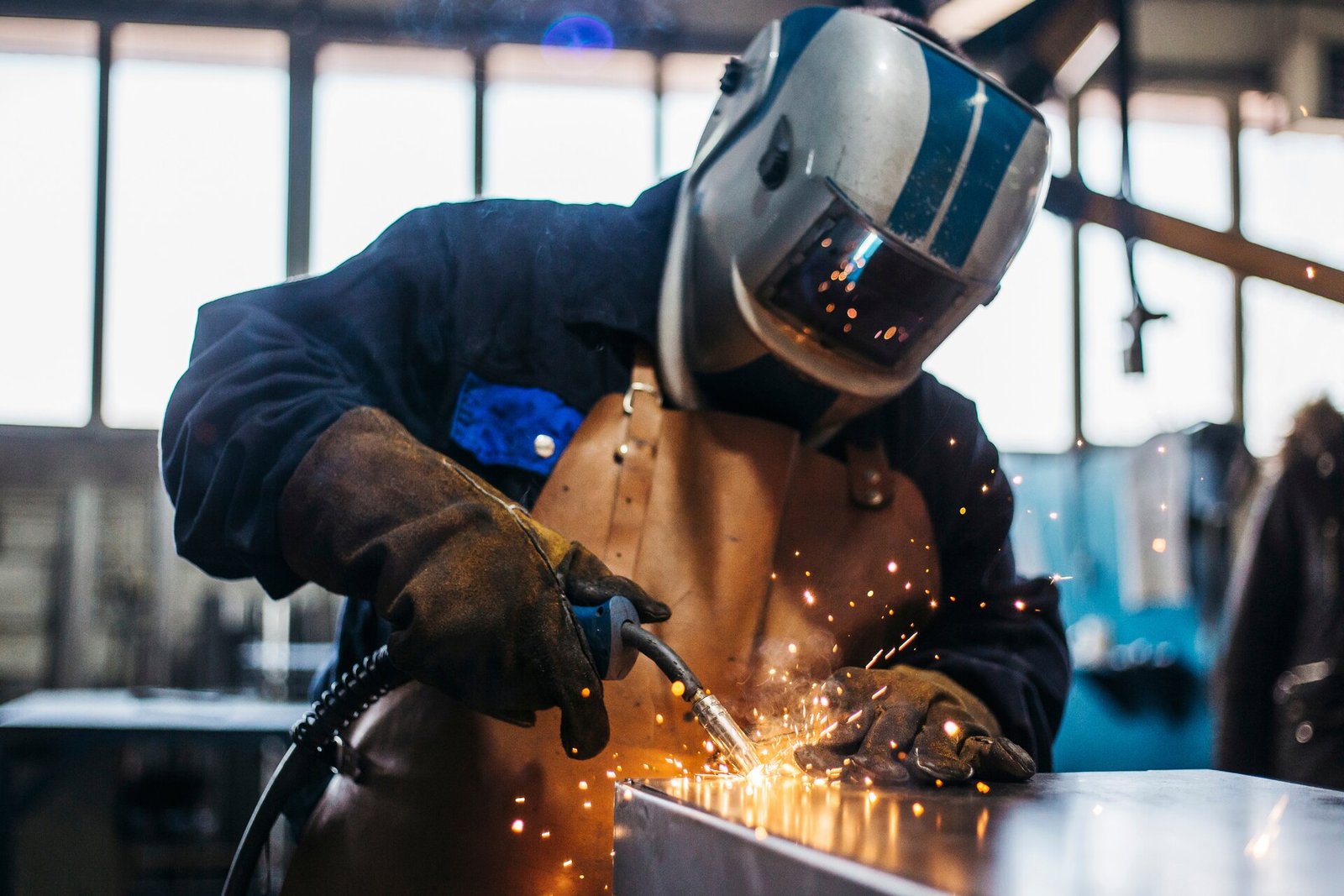 Soudeur à l'œuvre dans un atelier industriel, gerbe d'étincelles.